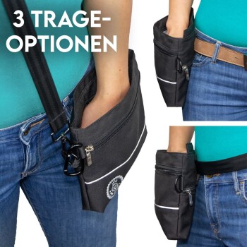 Eine Frau in einem türkisfarbenen Shirt und Jeans demonstriert eine schwarze Tragetasche für Haustiere mit drei Trageoptionen, ausgestattet mit einem Reißverschluss und einem Clip.
