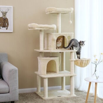 Ein beiger Kratzbaum für Katzen mit mehreren Ebenen und Kratzpfosten, mit einer grauen getigerten Katze, die klettert, und einer orangefarbenen Katze, die aus einem Versteck schaut.