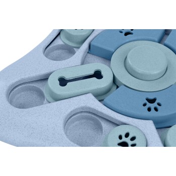 Eine Nahaufnahme eines bunten interaktiven Hundepuzzlespielzeugs mit verschiedenen Formen, darunter ein Knochen und Pfotenabdrücke, in Blau- und Grautönen.