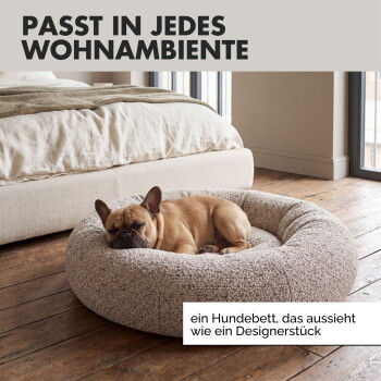 Ein entspannter Französischer Bulldogge, die sich auf einem weichen, runden Bouclé-Hundebett zusammenrollt, mit sichtbarem "Bouclé-Stoff" und "hochwertiger Bouclé-Stoff."