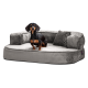 Ein kleiner schwarz-brauner Hund, der auf einem plüschigen, grauen Haustierbett mit einer unterstützenden Rückenlehne und einem dekorativen Kissen entspannt.