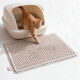 Rotgetigertes Kätzchen steigt aus einer abgedeckten beigen Katzentoilette auf eine strukturierte beige Streufangmatte.