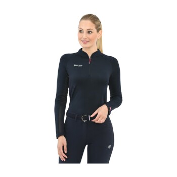 Eine Frau trägt ein marineblaues Langarmoberteil mit einem Reißverschlusskragen und einem Logo, das 'SPOOKS' auf der Brust zeigt, kombiniert mit dunklen Reithosen.