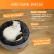 Eine weiße Katze entspannt sich in einem runden grauen Haustierbett. Der Text enthält "Auch für Hunde" und "Für kleine und große Katzen."