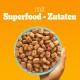 Eine Hand hält eine türkisfarbene Schüssel, die mit kleinen, braunen Haustierfutterkibbles gefüllt ist, mit dem Text "mit Superfood - Zutaten" auf einem orangefarbenen Hintergrund.