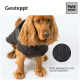 Ein goldener Cocker Spaniel trägt einen stylischen schwarzen gesteppte Hundemantel, mit dem Text 'Gesteppt' und 'Edel gesteppt und leicht wattiert' angezeigt.