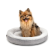 Ein flauschiger Hund sitzt in einem gemütlichen, runden grauen Hundebett mit einem weichen, plüschigen Innenraum.
