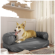 Ein glücklicher Corgi liegt auf einem grauen Haustierbett in einem gemütlichen Raum mit hellen Vorhängen, einer Hundeschüssel und einem Kauspielzeug in der Nähe.