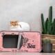 Eine flauschige orange-weiße Katze ruht auf einer rosa Dose mit der Aufschrift 'Sardinen aus dem Meer', mit einem Metall-Pull-Tab, neben einem Topf mit einem Kaktus.