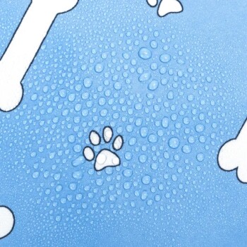 Eine blaue Haustiermatte mit weißen Knochenmustern und einem kleinen Pfotenabdruck, bedeckt mit Wassertropfen.