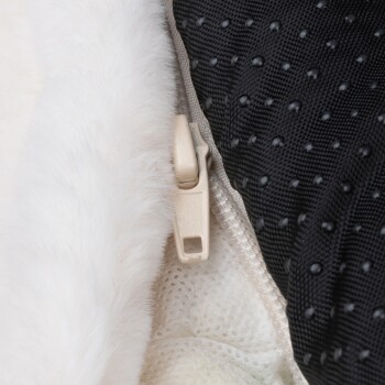 Nahaufnahme eines Reißverschlusses eines Haustierbettes, mit weichem weißen Fell auf einer Seite und einem strukturierten schwarzen Stoff auf der anderen, der hochwertige Materialien zeigt.