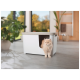 Een fluffy oranje kat staat naast een witte kattenbak met een uitsnede ingang, geplaatst in een heldere, moderne kamer met planten.