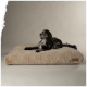 Ein schwarz-weißer Hund ruht auf einem plüschigen, beigen Hundebett mit einer gesteppten Textur, das ein Scruffs-Logo an der Seite trägt.