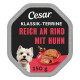 Cesar Hundefutteretikett mit der Aufschrift 'KLASSIK-TERRINE REICH AN RIND MIT HUHN, 150 g', einem lächelnden weißen Hund und Fleisch auf einem Teller.