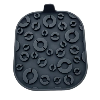 Schwarze Silikon-Haustierfütterungsmatte mit verschiedenen kreisförmigen erhöhten Mustern, die ein Verrutschen und Verschütten verhindern sollen.