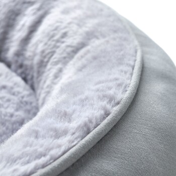 Nahaufnahme eines weichen, plüschigen Haustierbettes mit einem grauen Außenstoff und einem flauschigen hellgrauen Innenfutter.