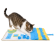 Getigert-weiße Katze schnuppert und stupst mit der Pfote an einer blau-gelben Schnüffel-Puzzlematte auf weißem Hintergrund.