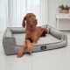 Brauner Hund mit rosa Halsband liegt auf einem grauen Tierlando Haustierbett in einem hellen Raum mit weißen Vorhängen.