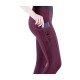 Nahaufnahme einer Frau in burgunderfarbenen Reitleggings mit Seitentasche, die ein Handy hineinlegt. Die Leggings zeigen das "EQUIVA"-Logo.