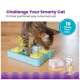 Eine verspielte getigerte Katze interagiert mit einem Puzzle-Futterspender mit gelben und weißen Leckerlischalen, der die geistige Anregung für Haustiere fördert.