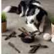 Eine Person hält eine Handvoll verschiedener Hundekauartikel, die verschiedene Texturen und Farben aufweisen, mit einem Abzeichen, das "Beste Qualität - 10 Jahre" in der Ecke angibt.