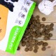 Eine teilweise geöffnete LECKER.PET-Tüte mit Haustierfutter, mit dunklem Futter, das auf einer Holzoberfläche verstreut ist, und die hohe Protein- und Vitaminwerte hervorhebt.