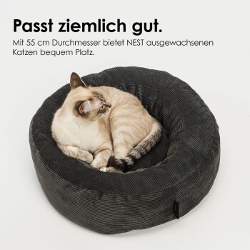 Katze zusammengerollt in einem dunkelgrauen Cord-Rundbett; deutscher Text oben: "Passt ziemlich gut." und "Mit 55 cm Durchmesser".