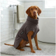 Ein grauer Hundemantel mit weicher Textur, mit einer Tasche und einem Etikett, das "THE DOG IDEA" liest.