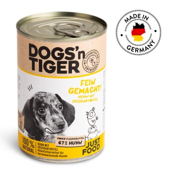 Eine Dose DOGS'n TIGER Hundefutter mit einem schwarz-weißen Welpenetikett, das "Fein gemacht! Huhn mit Süßkartoffel" und "100% NATURAL" angibt.