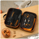 Offenes schwarz-orangefarbenes Haustierpflegeset auf Holztisch mit Schere, Kämmen, orangefarbenem Handtuch und Schale mit Hundesnacks.
