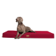 Ein grauer Weimaraner-Hund, der auf einem roten Haustierbett liegt und aufmerksam zur Seite schaut, mit einem kleinen Logo an der Seite des Bettes.