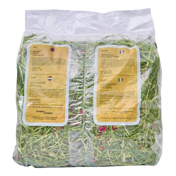 Przezroczysta torba z suszoną trawą z kolorowymi płatkami kwiatów, oznaczona w wielu językach jako naturalna i wolna od kurzu dla zwierząt.