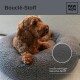 Ein brauner Hund, der auf einem runden grauen Bouclé-Haustierbett ruht, mit sichtbarem "Bouclé-Stoff" und "hochwertiger Bouclé-Stoff."