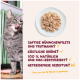 Getigerte Katze leckt sich die Lippen neben einem Teller mit zerkleinertem Hähnchen; deutsche Beschriftung: 'Saftige Hühchenfilets... Getreidefreie Rezeptur? Ja!'
