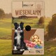 Hundefuttertüte mit einem Border Collie, beschriftet mit "WIESENLAMM mit Kartoffeln & Heidelbeeren, Glutenfrei," zeigt Lamm, Kartoffeln und Heidelbeeren.