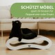 Eine schwarze Katze entspannt sich auf einem gebogenen Kratzbaum mit weißem Sockel, der den Text zeigt: 'SCHÜTZT MÖBEL spart dir Kosten.'