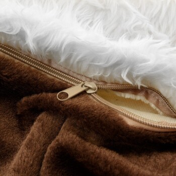 Nahaufnahme einer Haustierdecke mit einer weichen braunen Unterseite und einer flauschigen weißen Oberseite, mit einem sichtbaren goldenen Reißverschluss.