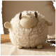Rundes, flauschiges, cremefarbenes Plüschspielzeug in Schaf-Form mit gestricktem Gesicht, winzigen Ohren und Beinen sowie zwei weißen Knopfaugen.