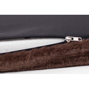 Nahaufnahme eines Haustierbettes mit einem schwarzen Reißverschlussbezug mit gepunkteter Textur und einem weichen braunen Kunstfellrand.