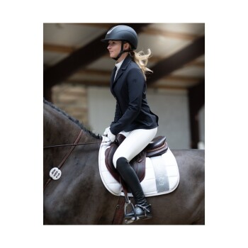 Ein Reiter in einer schwarzen Jacke und einem Helm sitzt auf einem braunen Pferd, trägt weiße Reithosen und schwarze Stiefel in einer Reithalle.