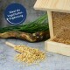 Holz-Vogelfutterspender mit Mischsamen, eine Schaufel Hafer daneben ausgekippt, und eine Sprechblase mit dem Text 'Ideal als Vogelfutter-Ergänzung.'