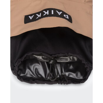 Beige-schwarze Haustierjacke mit Kapuze und elastischem Kordelzug, glänzendem schwarzen Innenfutter und Etikett mit der Aufschrift 'PAIKKA' (verkehrt herum).