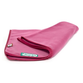 Eine gefaltete pinke Haustierdecke mit einem grünen "Doctor Bark"-Label und einem kleinen Etikett in der Ecke, das ihre weiche Textur zeigt.