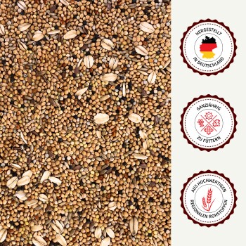 Nahaufnahme von gemischtem Vogelfutter mit deutschen Textabzeichen „Made in Germany“, „Ganzjährig füttern“ und „Aus hochwertigen regionalen Rohstoffen“.