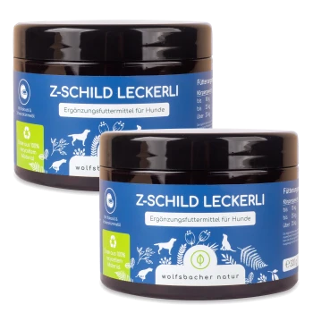 Zwei Gläser "Z-Schild Leckerli," ein Ergänzungsfutter für Hunde, mit einem blauen Etikett mit weißem Text und Illustrationen von Hunden und Pflanzen.