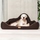 Ein großer weißer Hund ruht bequem in einem braunen Haustierbett, teilweise von einer Decke bedeckt, in einem modernen Innenraum.