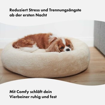 Ein Cavalier King Charles Spaniel entspannt sich auf einem plüschigen Hundebett. Text: "Reduziert Stress und Trennungsangst von der ersten Nacht."