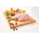 Ein Holzschneidebrett hält rohe Hähnchenbrust mit grünen Erbsen, Heidelbeeren, Apfelscheiben, Ingwer, Champignons und Honig.