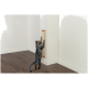 Un chat tigré grattant un poteau à gratter vertical fixé à un mur blanc dans une pièce minimaliste avec un sol en bois.