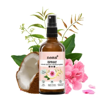 Eine Sprühflasche mit der Aufschrift "noms+ ZPRAY" mit einem Anti-Zecken-Komplex, umgeben von Kokosnuss- und Blütendekoren, die vegane Haustierpflege fördert.